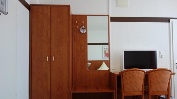 Une pièce comprenant une armoire en bois, un bureau avec un téléviseur et deux chaises.