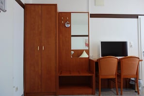 A room with a wooden wardrobe, a desk with a television, and two chairs. - Parkhotel Friedrichstraße (Giessen)