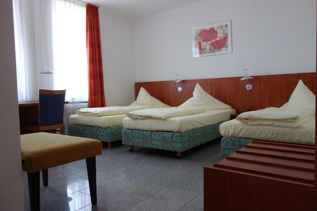 Habitación de hotel con dos camas, un escritorio y una silla.