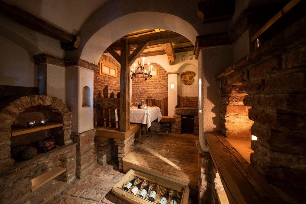 Ein rustikaler Innenraum mit Steinwänden, einem Kamin und einer hölzernen Bank.