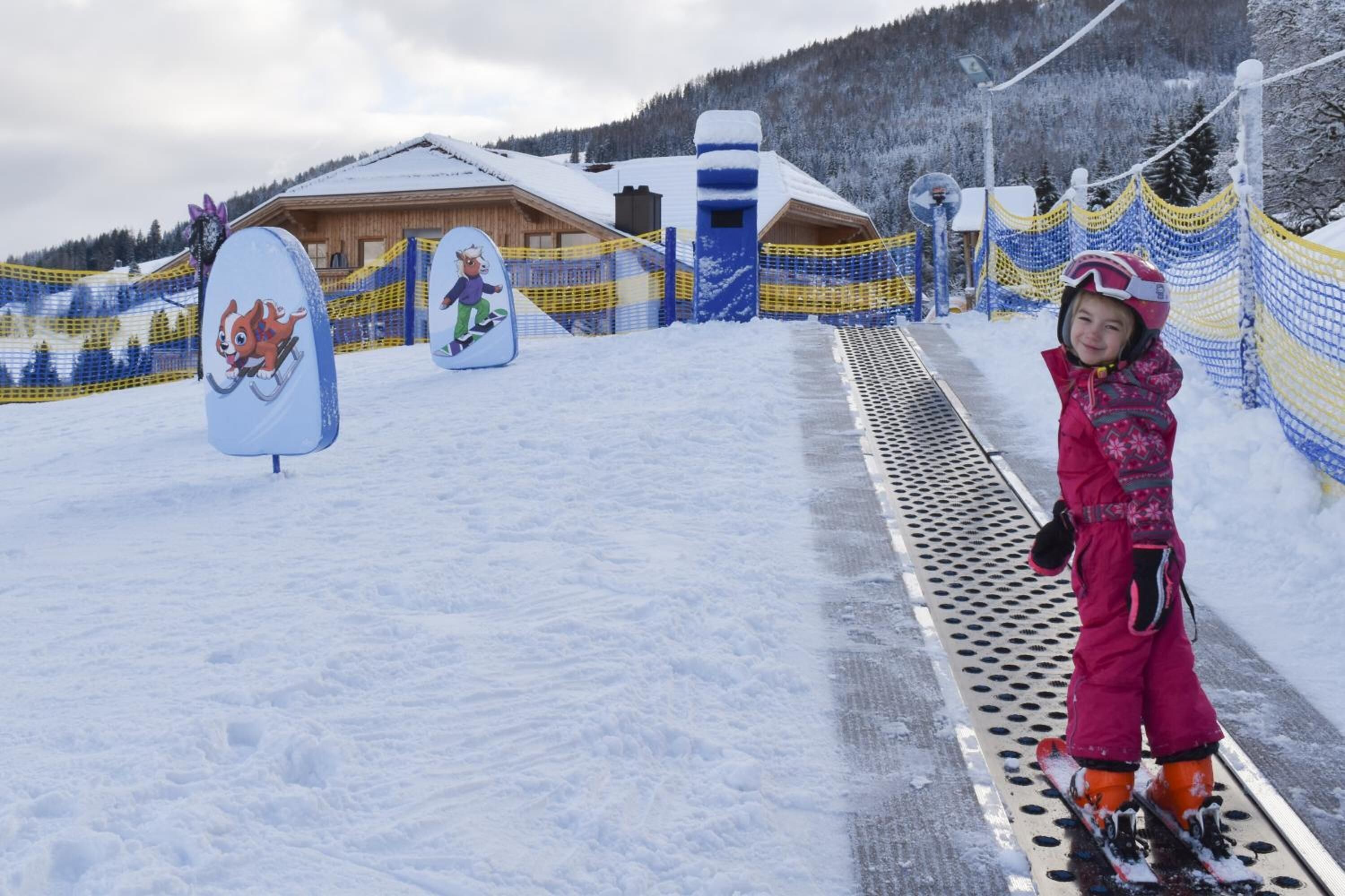 Pista de esquí nevada con una cabaña de madera y una valla.