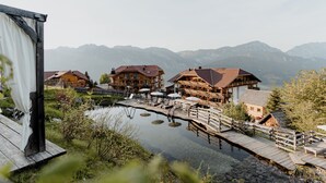 A lakeside hotel with wooden buildings, a dock, and mountains in the background.