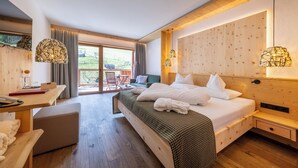 A modern hotel room with a wooden bed, a desk, and a balcony with a view of the countryside.