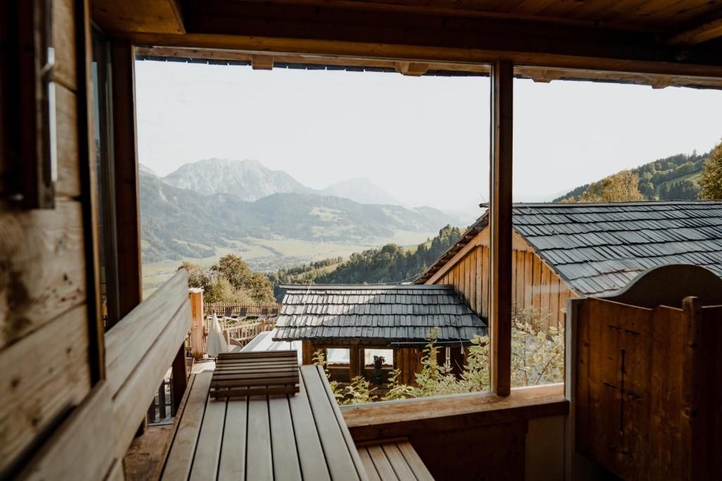 Une cabane en bois offrant une vue sur les montagnes grâce à de grandes fenêtres.