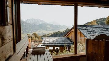 Une cabane en bois offrant une vue sur les montagnes grâce à de grandes fenêtres.