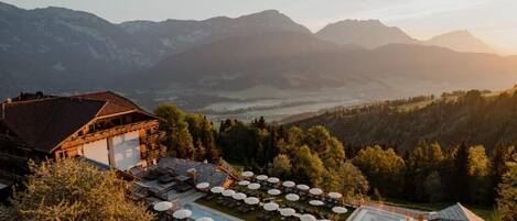 A hotel with a pool area, outdoor seating, and mountain views.