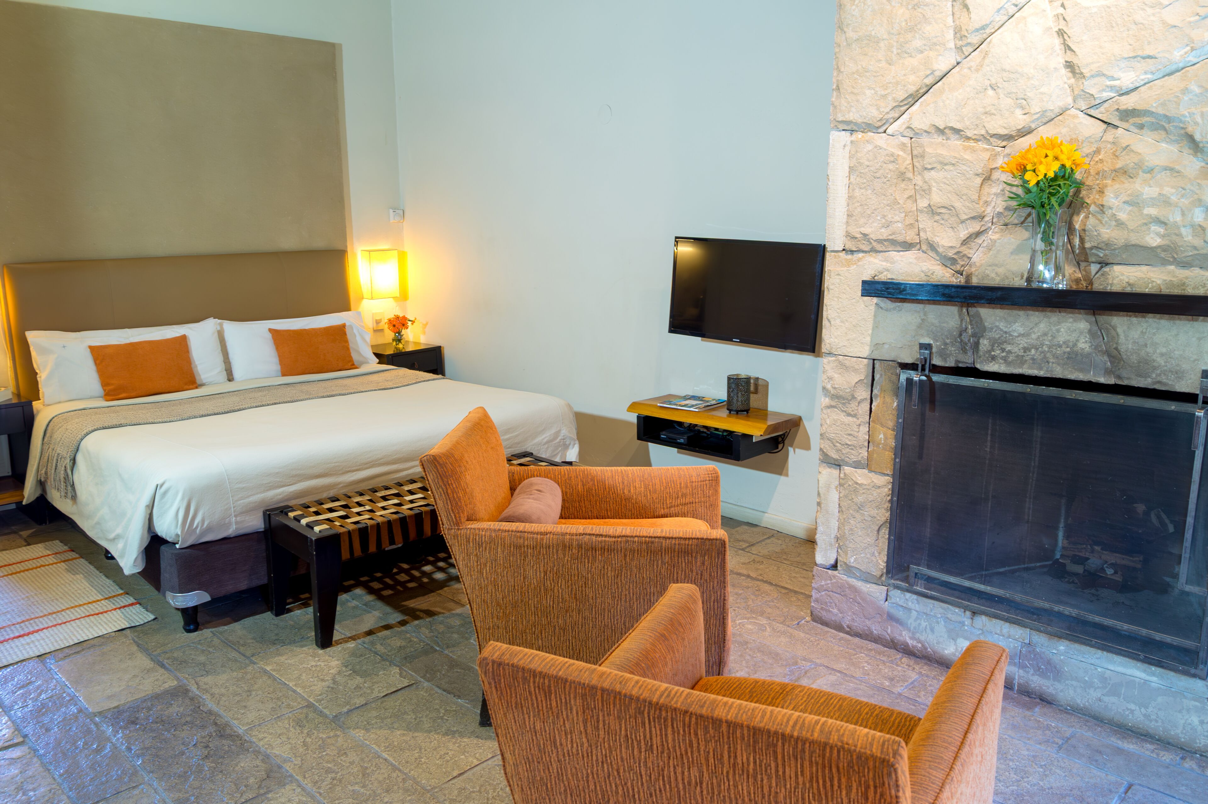 A hotel room with a bed, a television, a fireplace, and a seating area.