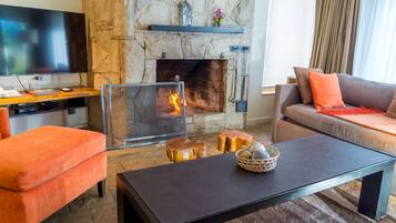 Un salon avec une cheminée en pierre, un téléviseur à écran plat, un canapé et une table basse.