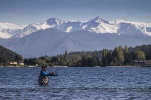 Eine Person beim Angeln in einem See vor einer Bergkulisse.