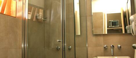Une salle de bain moderne avec une douche à parois de verre, un lavabo blanc et un miroir au-dessus du lavabo.