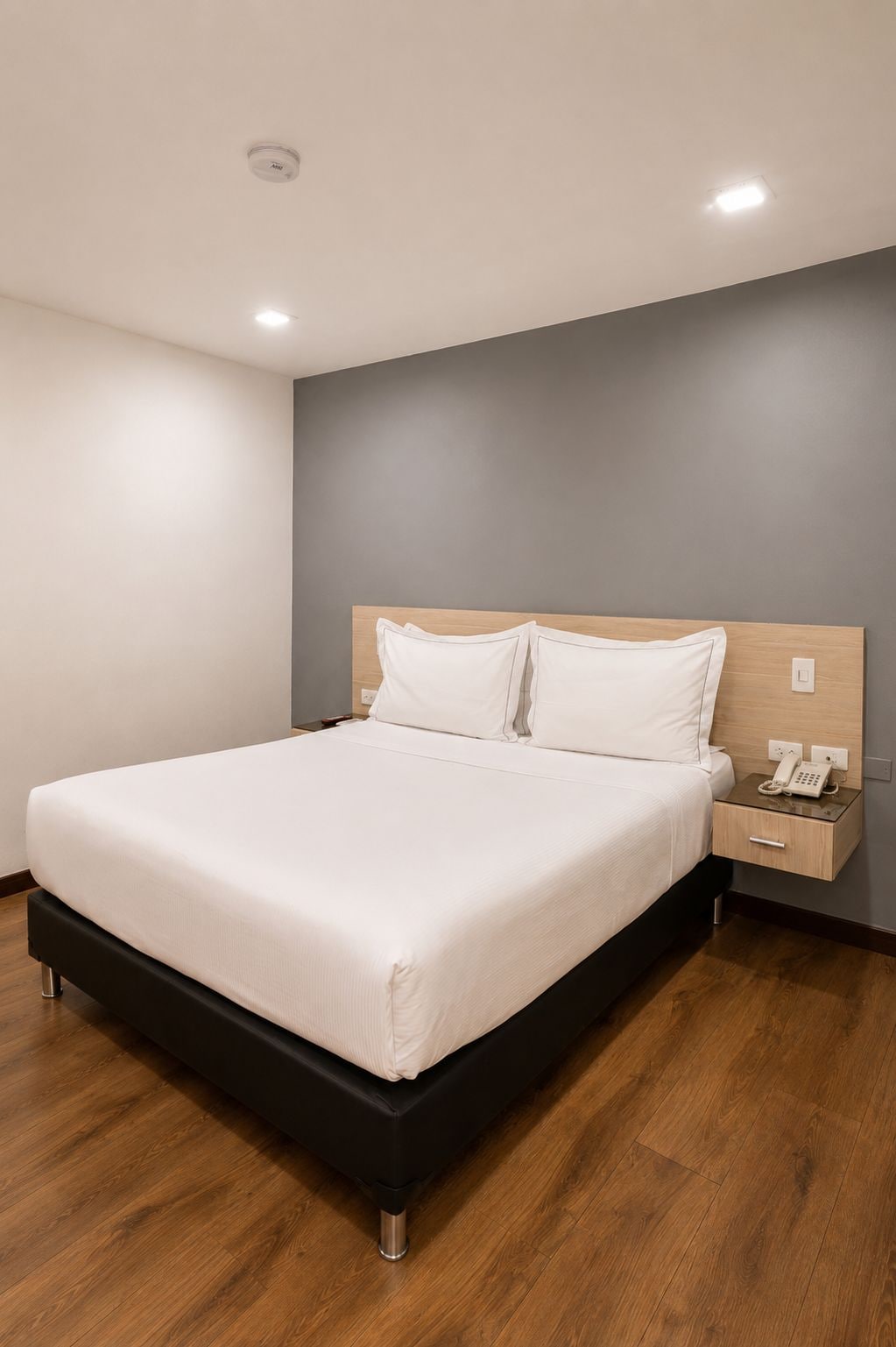 A modern bedroom with a bed, bedside tables, and a telephone.