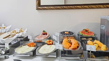A buffet with various food options including fruits, cheeses, and meats.