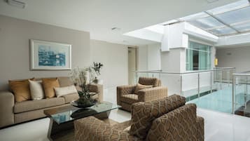 A modern interior with a glass ceiling, a sofa set, a coffee table, and a framed artwork on the wall.