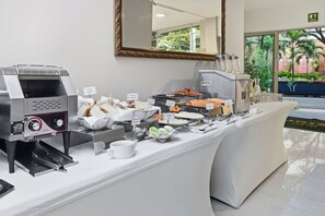 A buffet setup with a coffee machine, various food items, and a coffee station. - Hotel Asturias Medellin (Medellín)