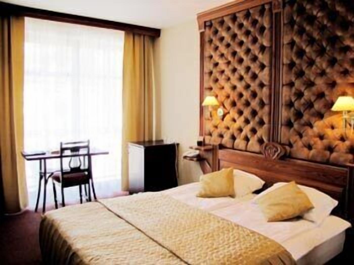 A hotel room with a large bed, a wooden headboard, a desk, and a chair.