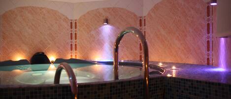 Un jacuzzi con paredes de azulejos y un grifo metálico.