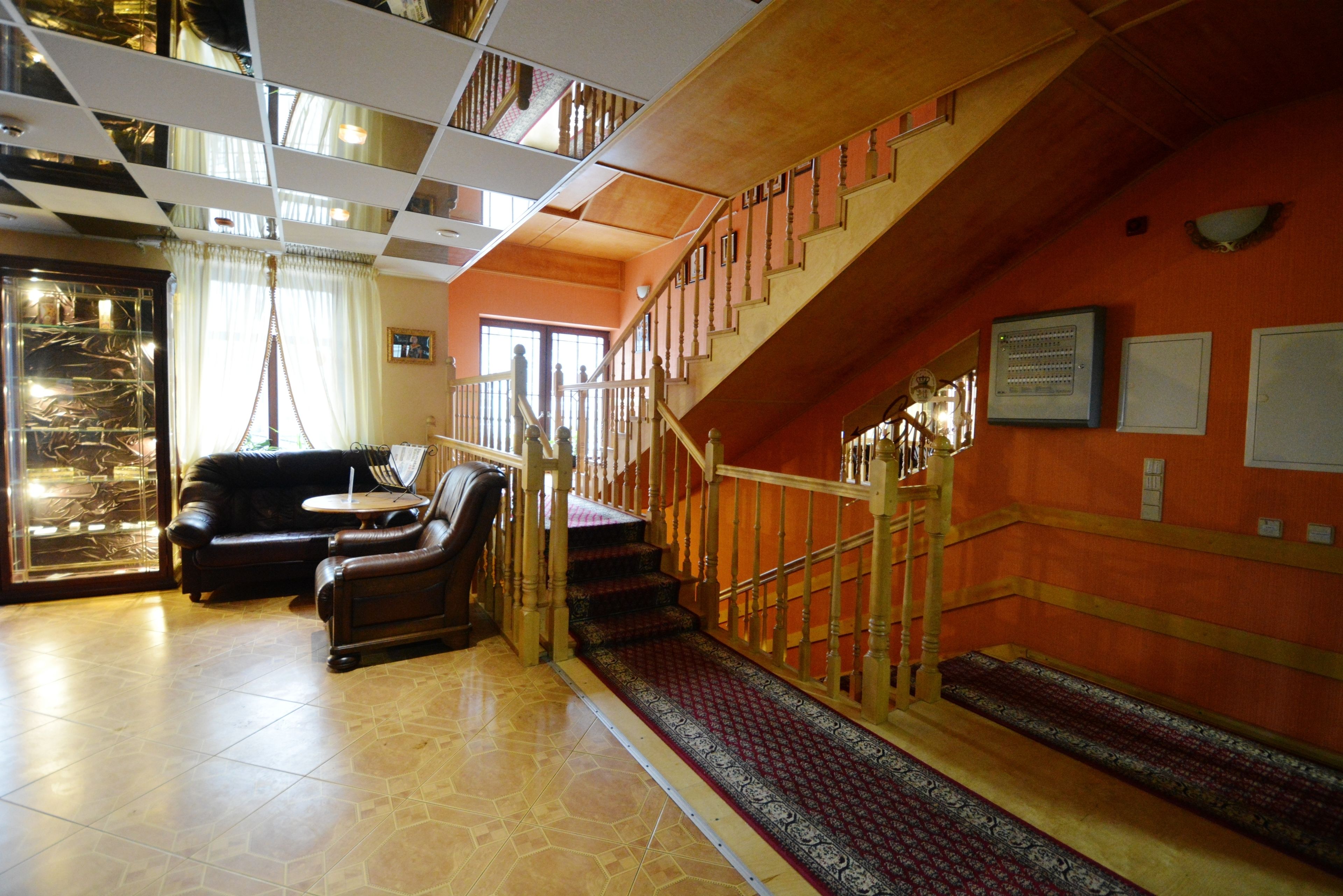 A spacious lobby with a staircase, leather seating, and a patterned carpet.