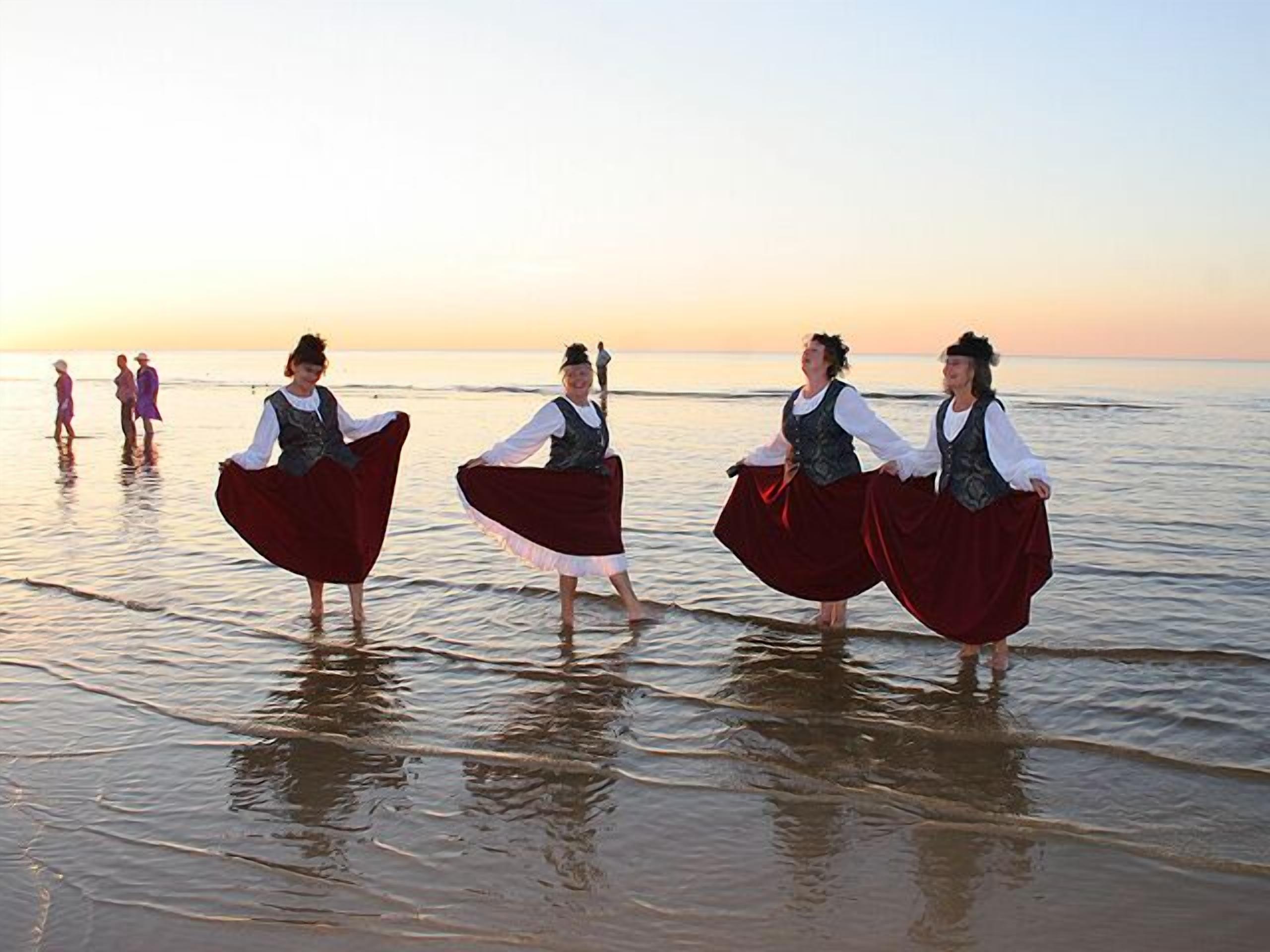 A beach scene with people in traditional attire.