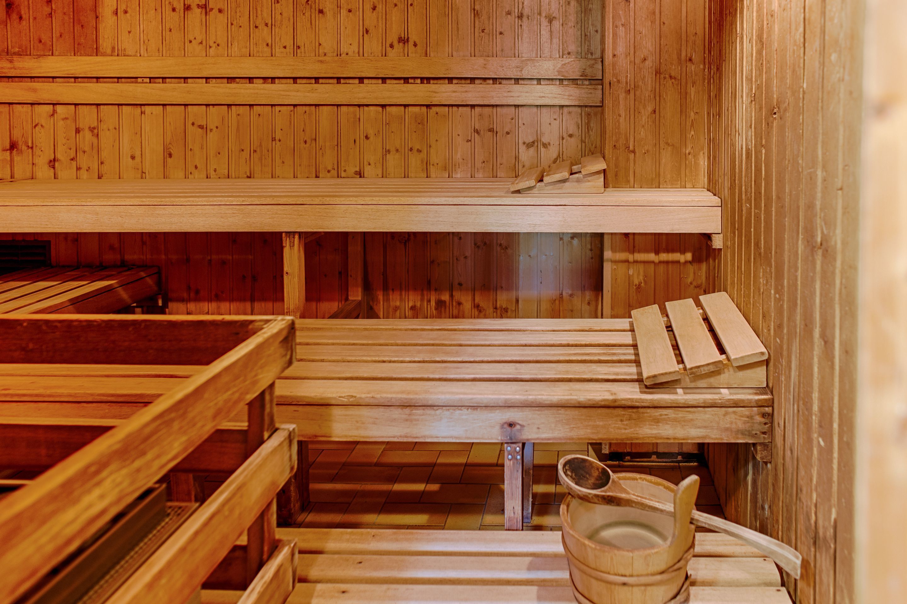 A sauna with wooden benches and a wooden bucket.
