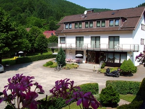 A two-story building with a balcony, a driveway, and a motorcycle parked in front.