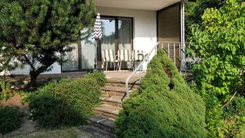 A residential property with a stone staircase leading to a covered outdoor seating area with chairs.