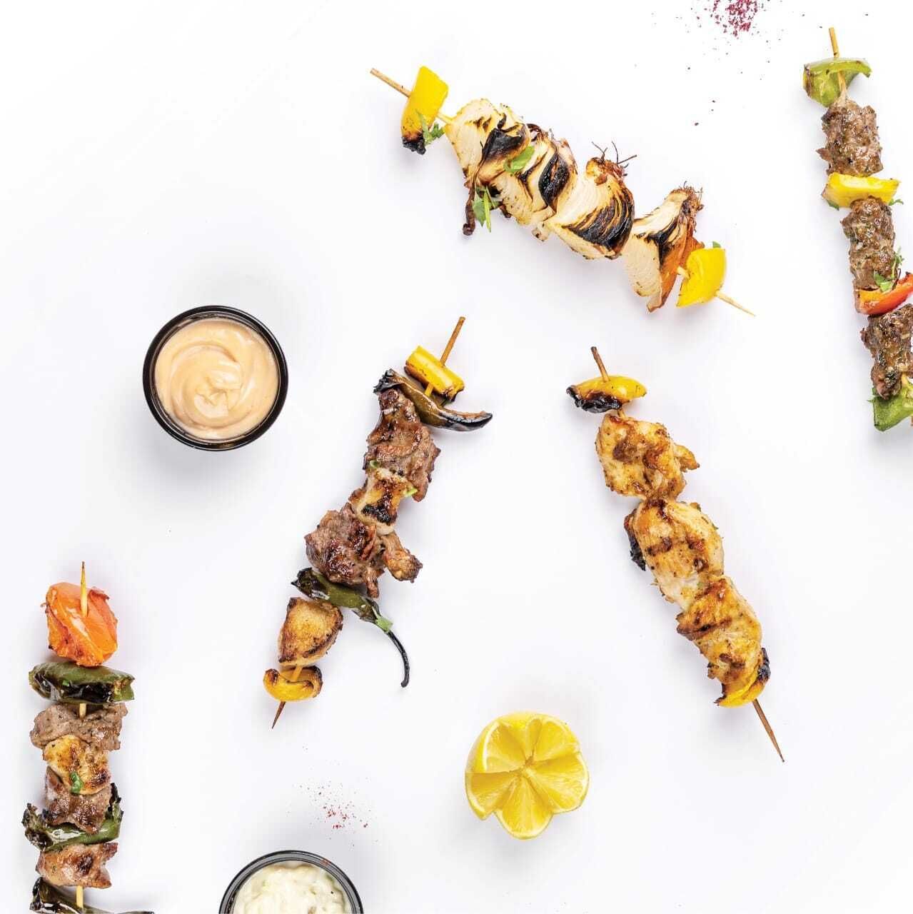 Various skewers of grilled meat and vegetables on a white background.
