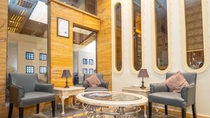 A lobby with two leather armchairs, a glass coffee table, and a mirror reflecting the room. - Captain's Hotel (Aqaba)