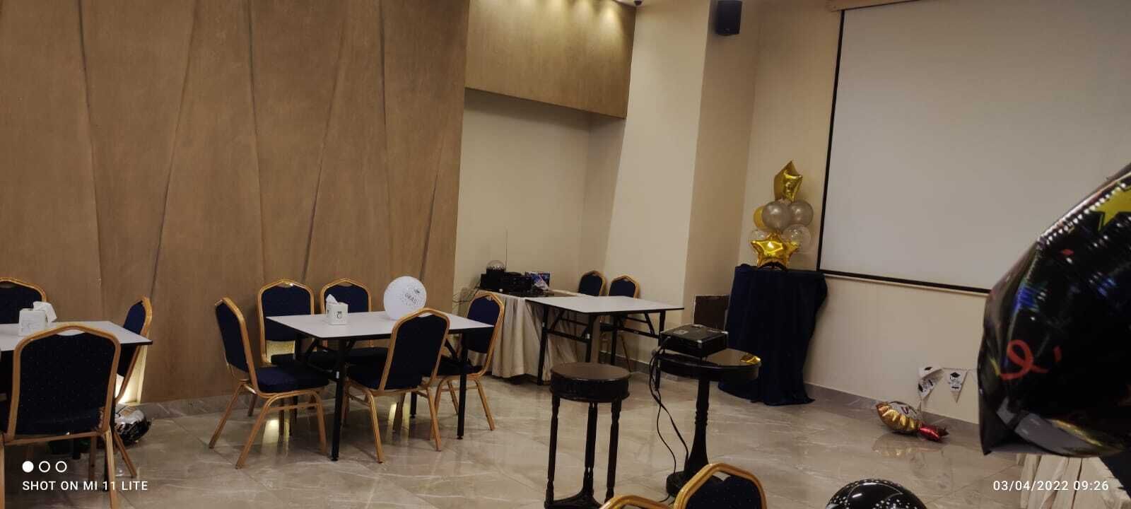 A conference room with tables and chairs, a projector screen, and a podium.