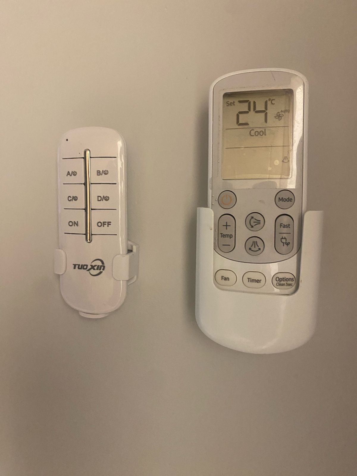 Termostato blanco y control remoto en una pared.