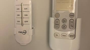 Termostato blanco y control remoto en una pared.