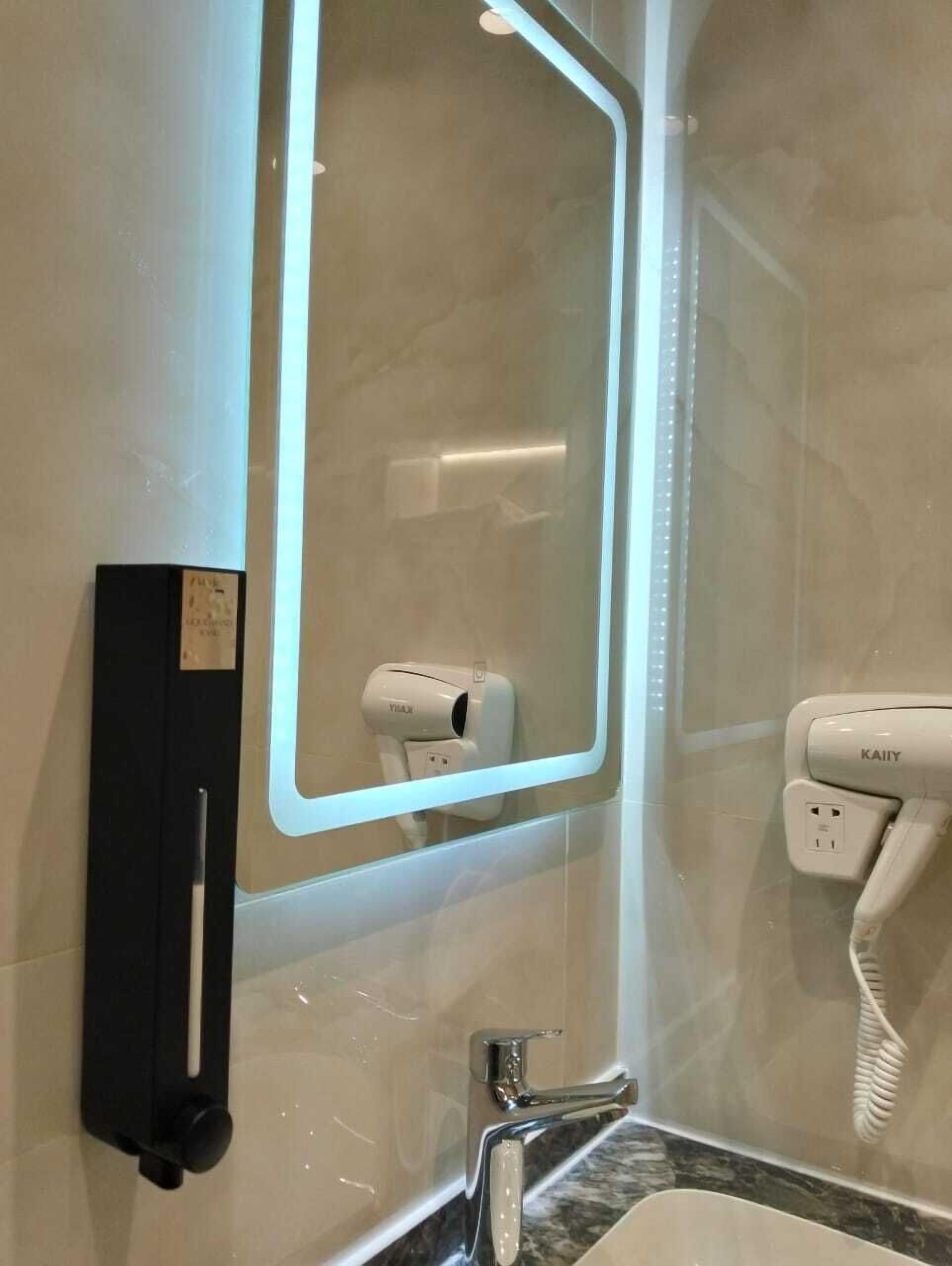 Une salle de bain équipée d’un miroir, d’un sèche-cheveux et d’un sèche-serviettes.