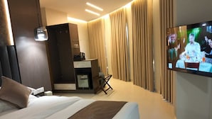 A hotel room with a large bed, a desk, a television, and a minibar. - Captain's Hotel (Aqaba)