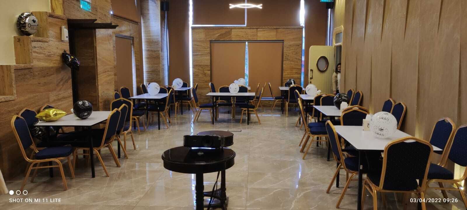 Una sala conferenze con tavoli, sedie, un pianoforte e un impianto audio.