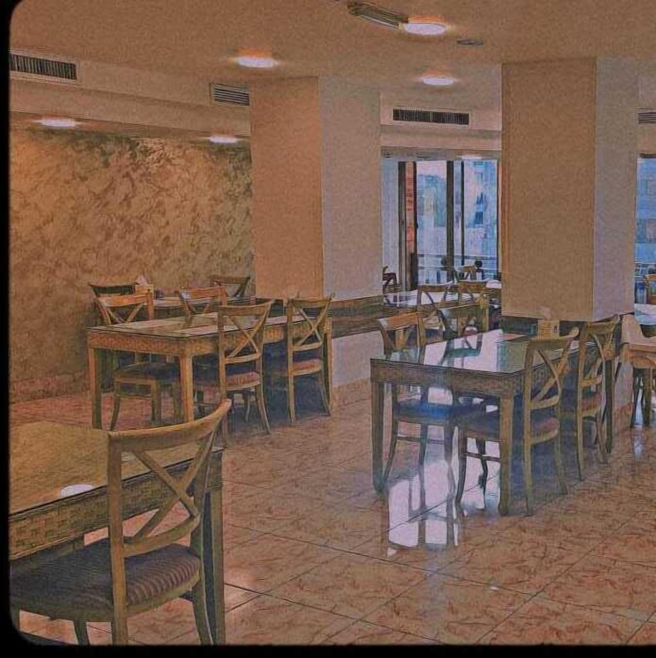 A dining area with wooden tables and chairs, a tiled floor, and a large window with a view.