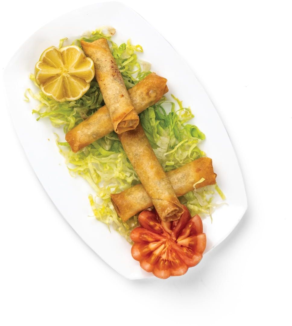 A plate of spring rolls with lettuce and a lemon wedge.