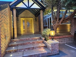A brick building with a wooden door, steps leading to a covered entrance, and a tree. - The Chester House Hotel - Previously Chester Court Hotel (Chester)