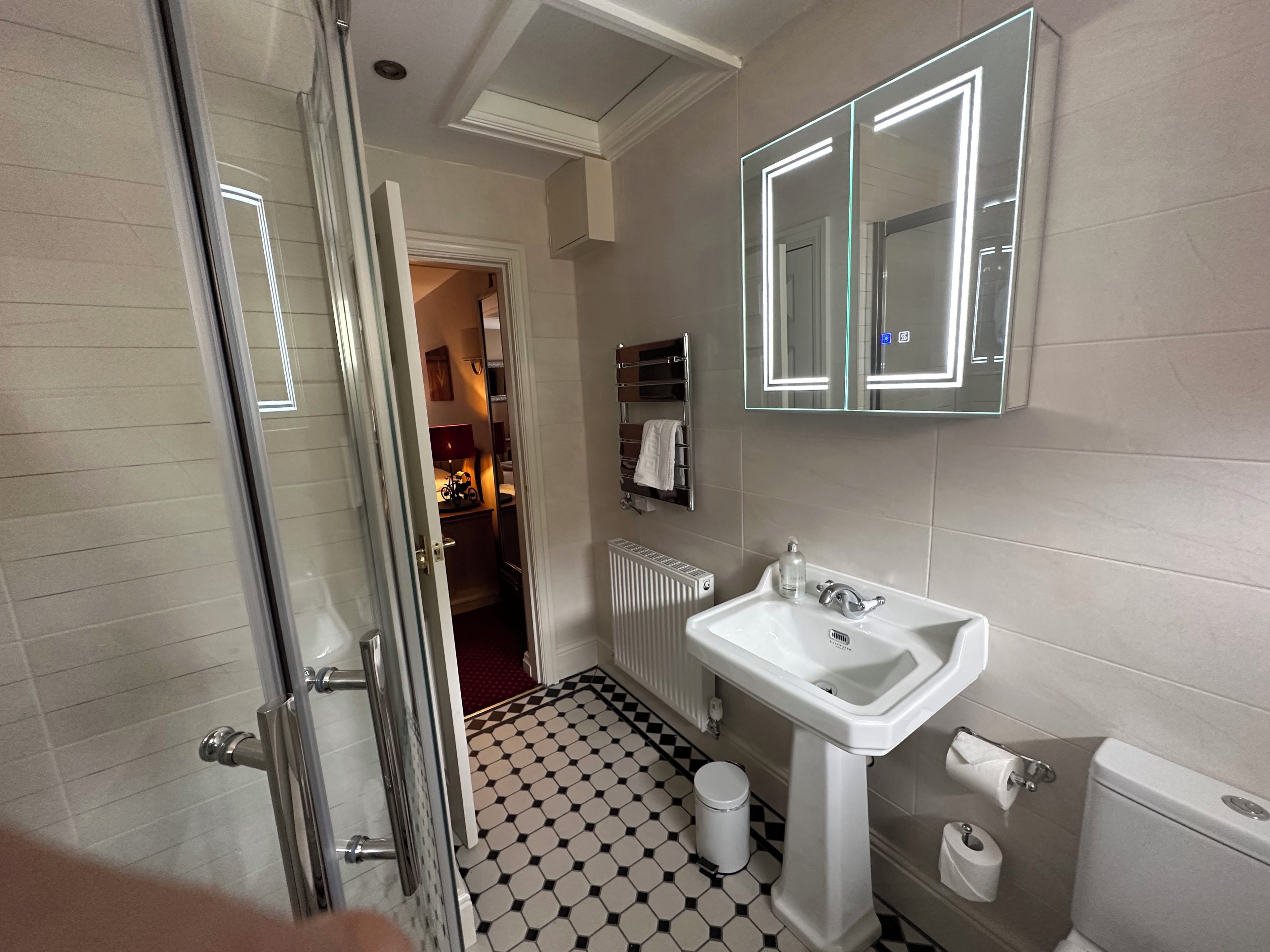 A bathroom with a white sink, a toilet, a mirror, and a radiator.