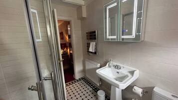 A bathroom with a white sink, a toilet, a mirror, and a radiator.