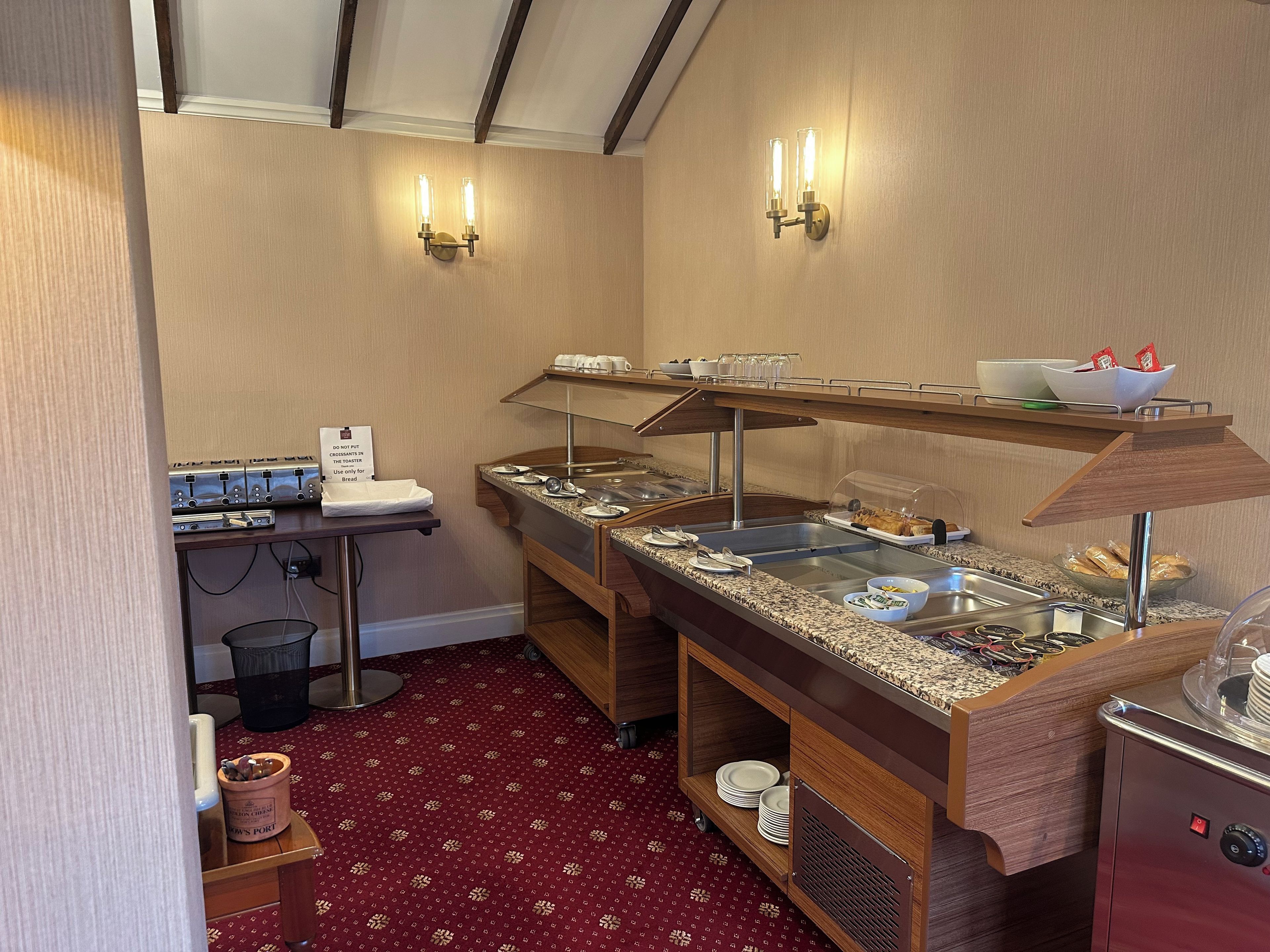 A buffet setup with a self-service station, a bread dispenser, and a trash bin.