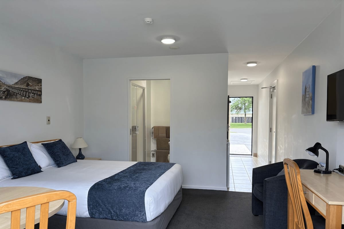 Una habitación de hotel con cama, escritorio, silla y televisor.
