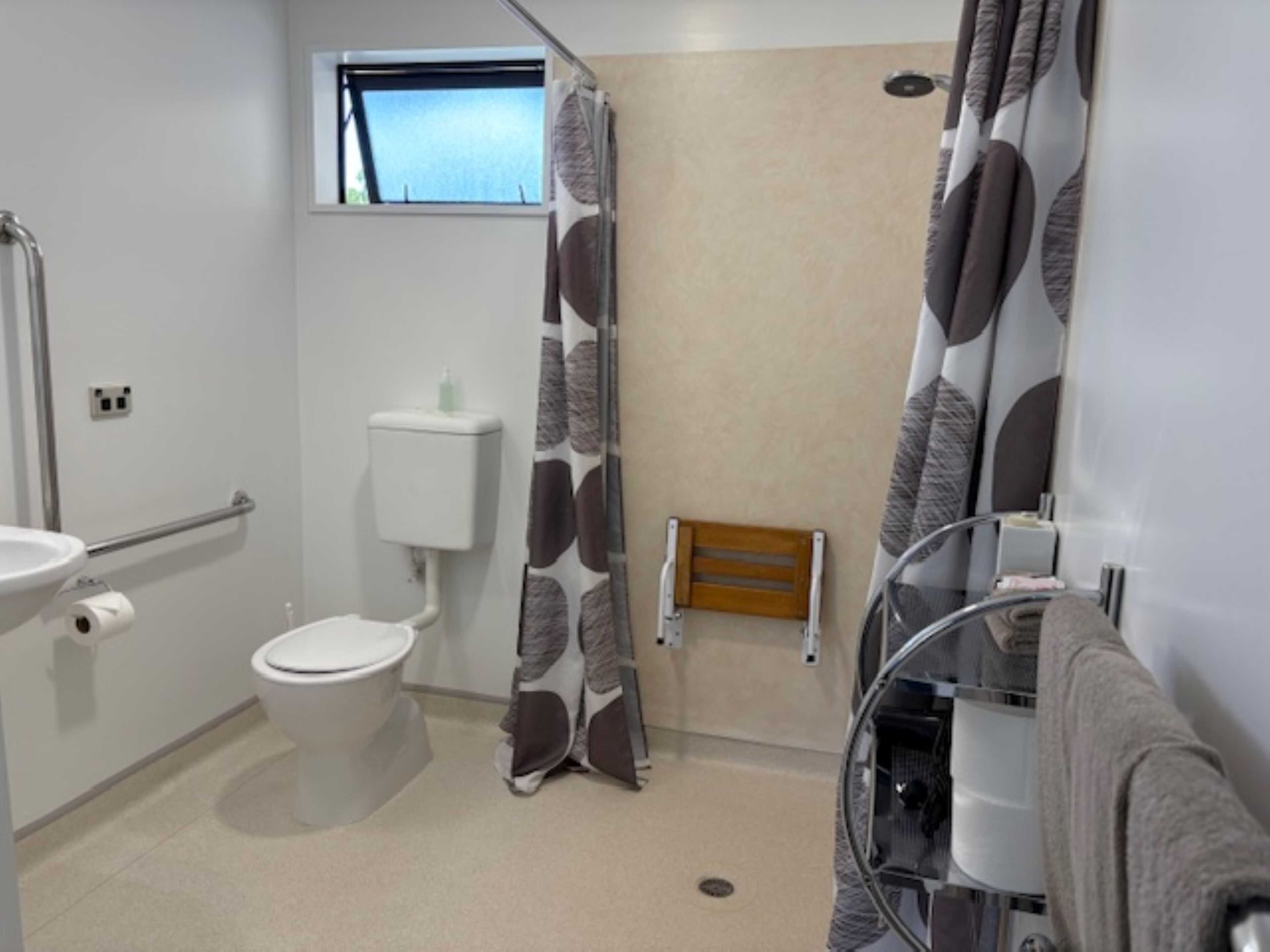 A bathroom with a toilet, a shower, a sink, and a window.
