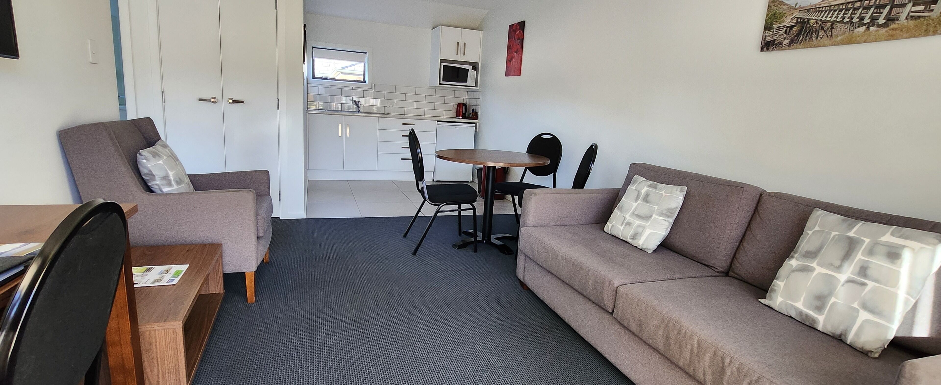 A compact living space with a sofa, a small dining table, and a kitchenette.
