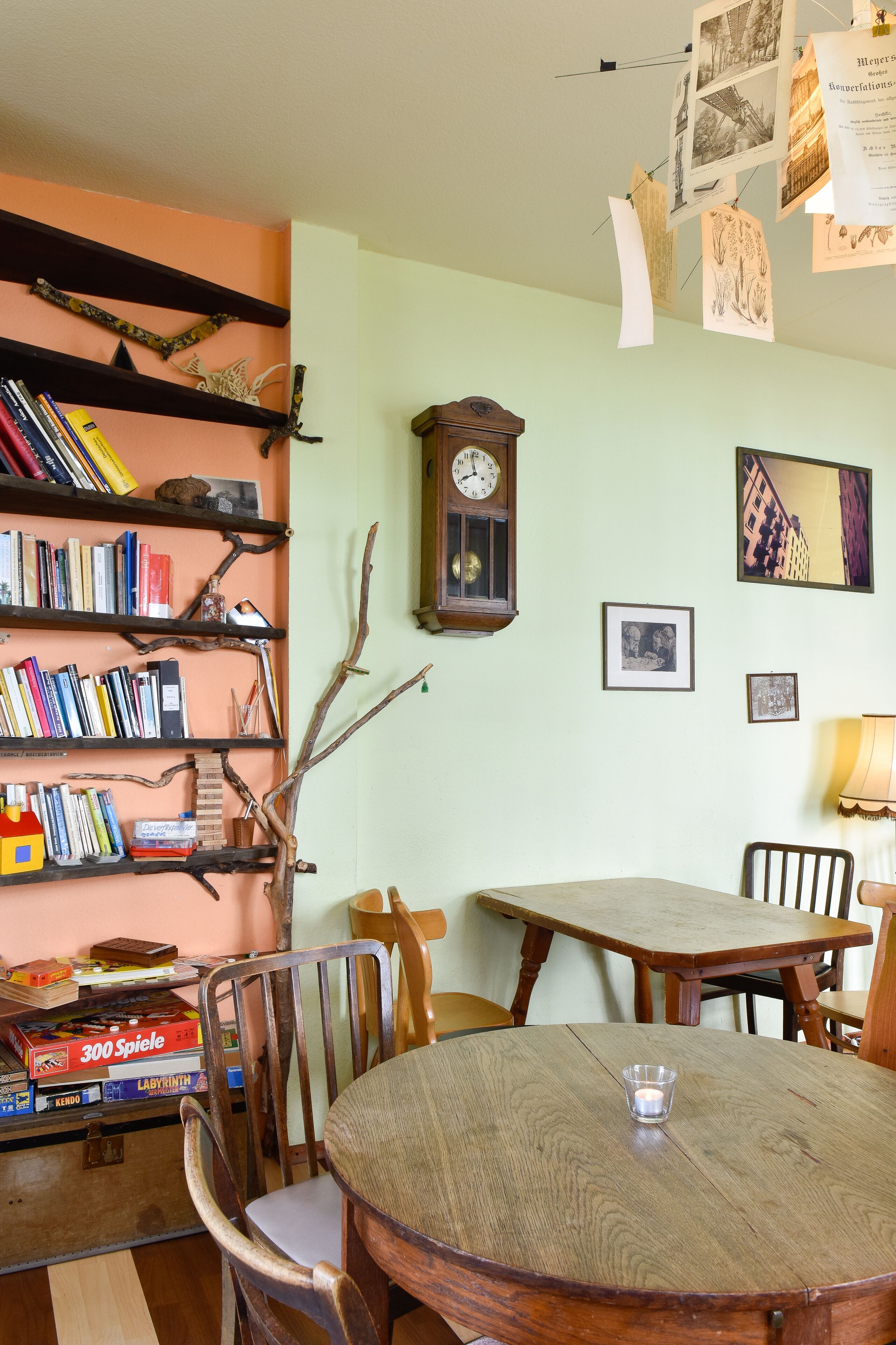 A dining area with a round wooden table, chairs, and a bookshelf filled with books.