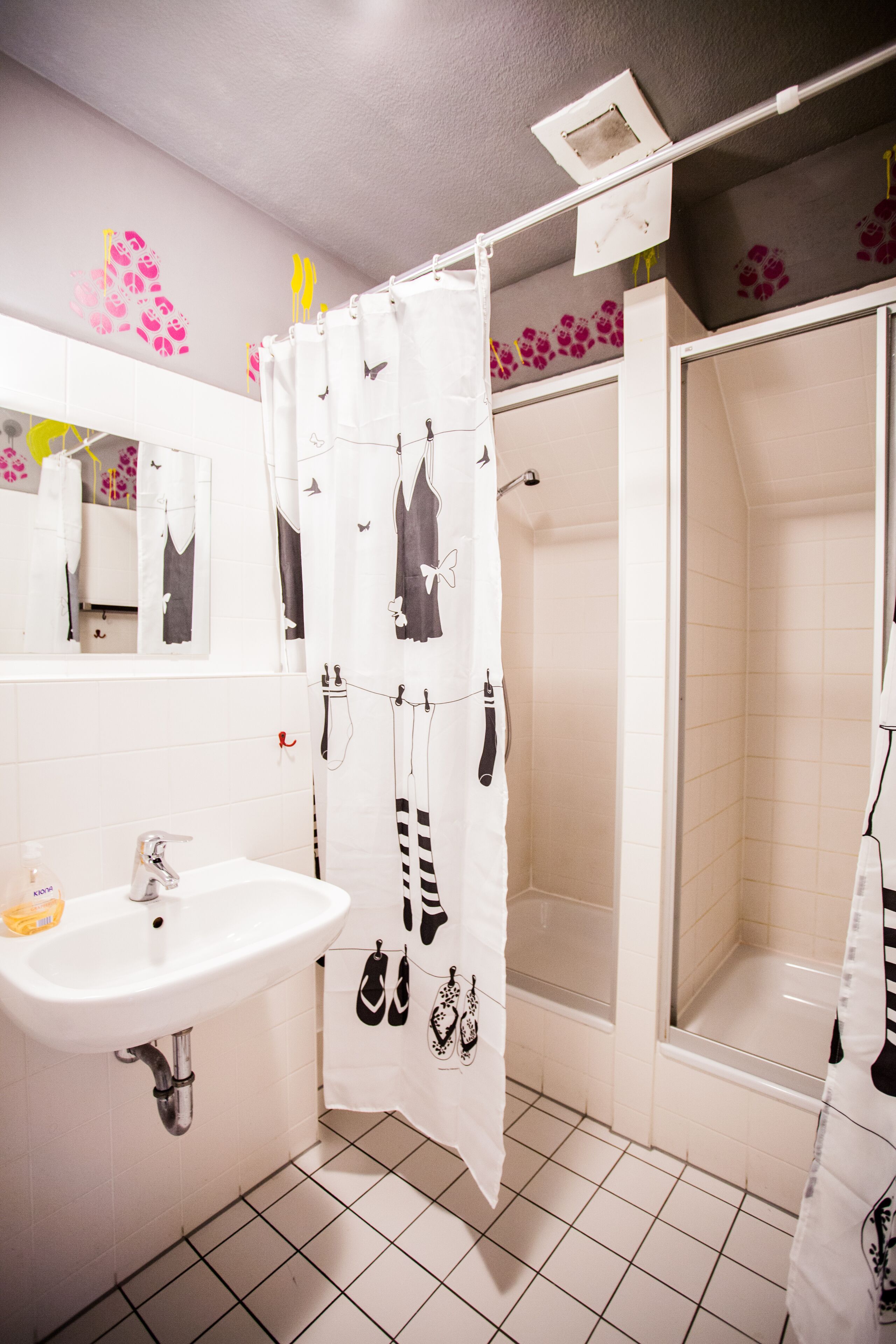 Un baño con lavamanos, espejo, ducha y piso de baldosas.