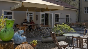 An outdoor seating area with tables and chairs, a large umbrella, and decorative planters. - Labyrinth Hostel (Weimar)