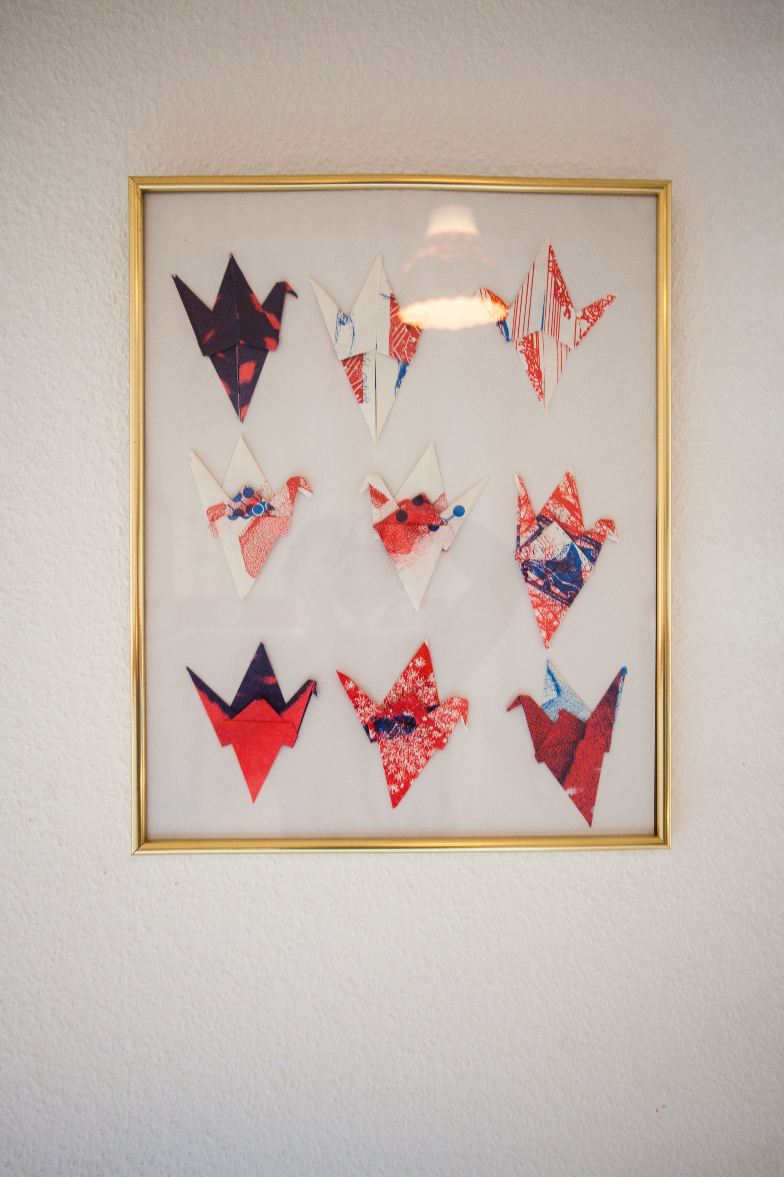 A framed collection of origami birds on a wall.