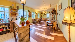 A spacious kitchen with a large island, wooden cabinets, and a view of the street. - Labyrinth Hostel (Weimar)