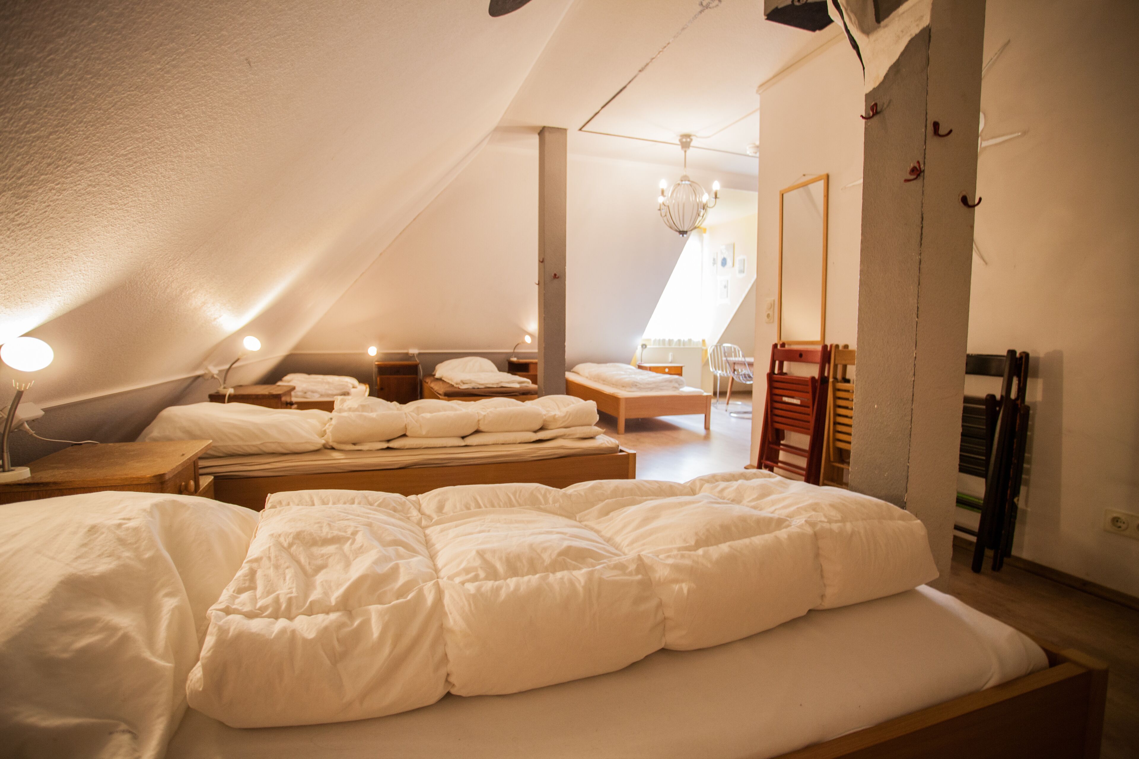Een ruime kamer onder de dakpannen met een groot bed, een houten bankje en een kleine tafel.