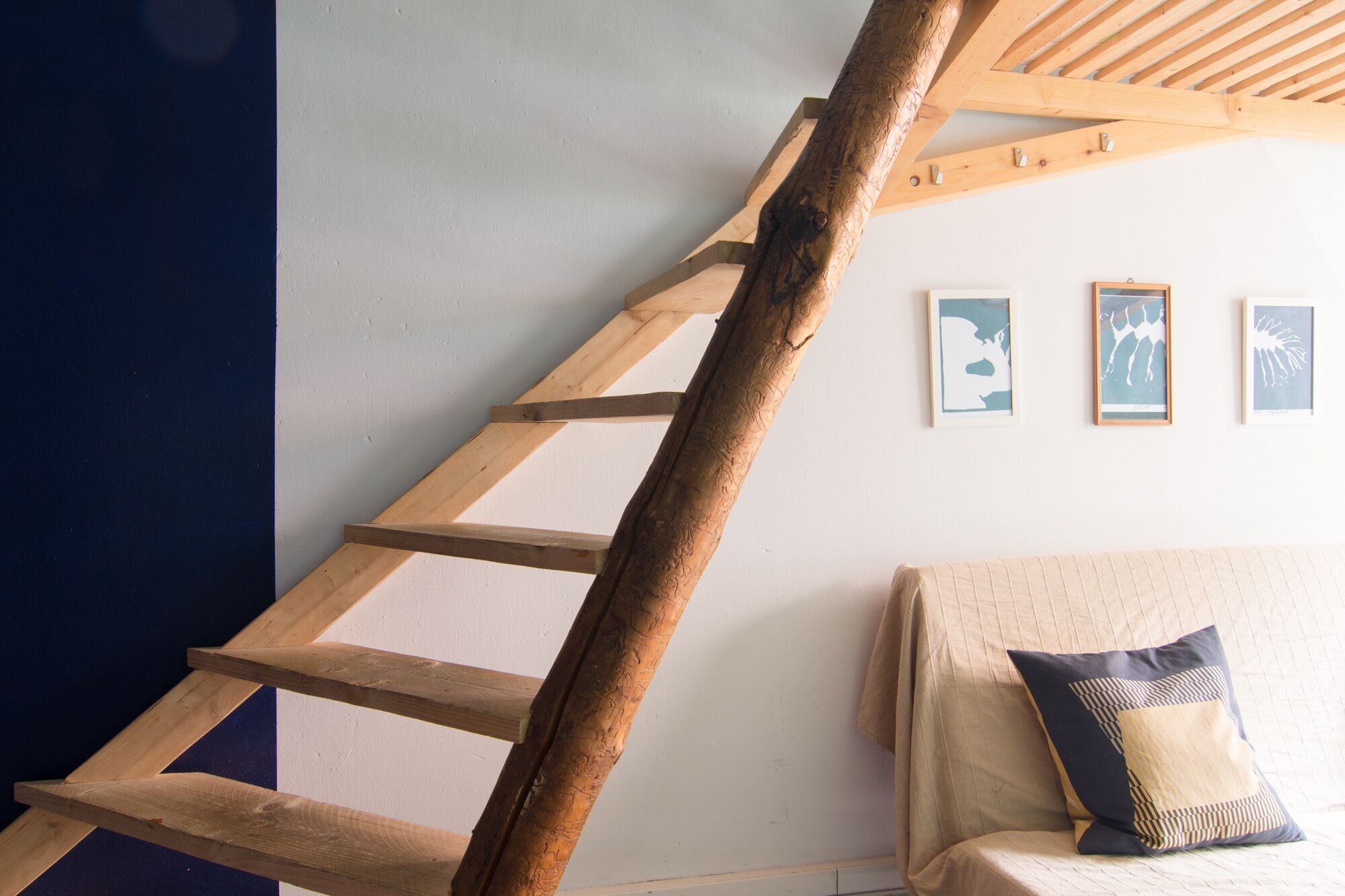 A wooden ladder against a wall with three framed pictures.