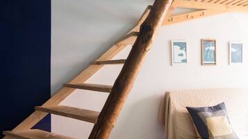 A wooden ladder against a wall with three framed pictures.